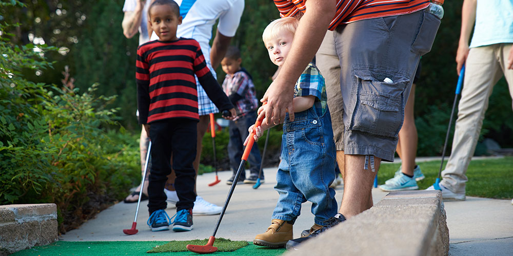 young boy playing mini golf